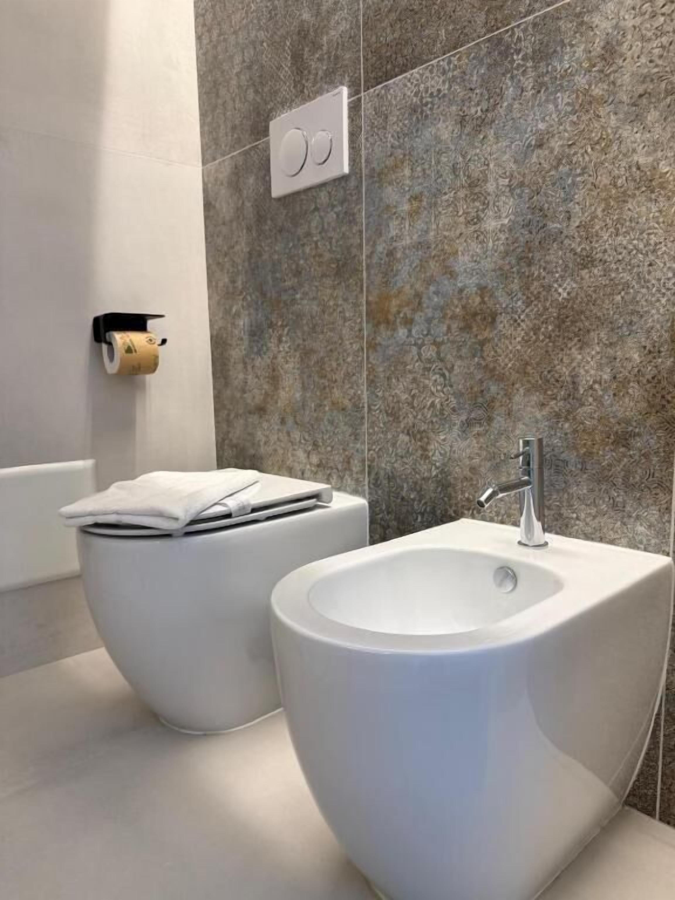Un baño moderno con un bidé, un inodoro y un lavabo.