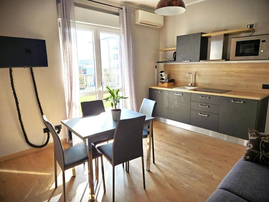 Una cocina moderna con microondas, horno y armarios de madera. Hay una mesa de comedor con sillas y una planta en maceta.