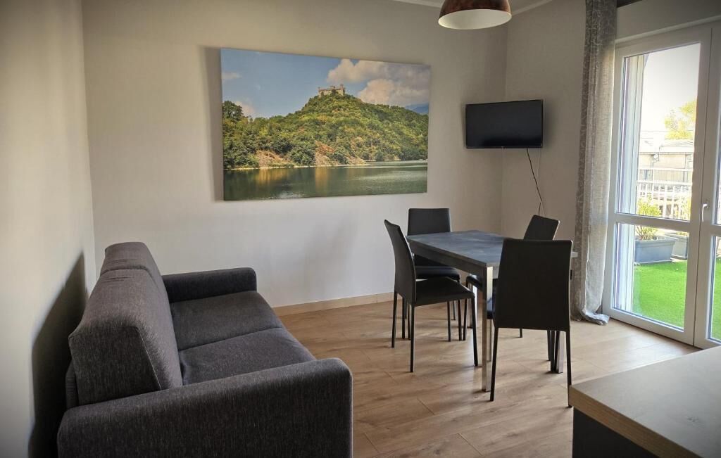 Una sala de estar moderna con un sofá, mesa de comedor, sillas y un cuadro de un paisaje.