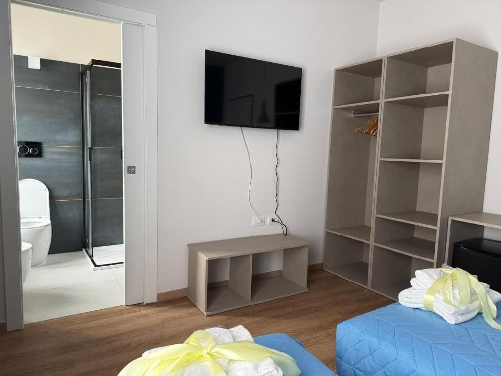 Ein modernes Schlafzimmer mit Fernseher, Kleiderschrank und Sitzbank.