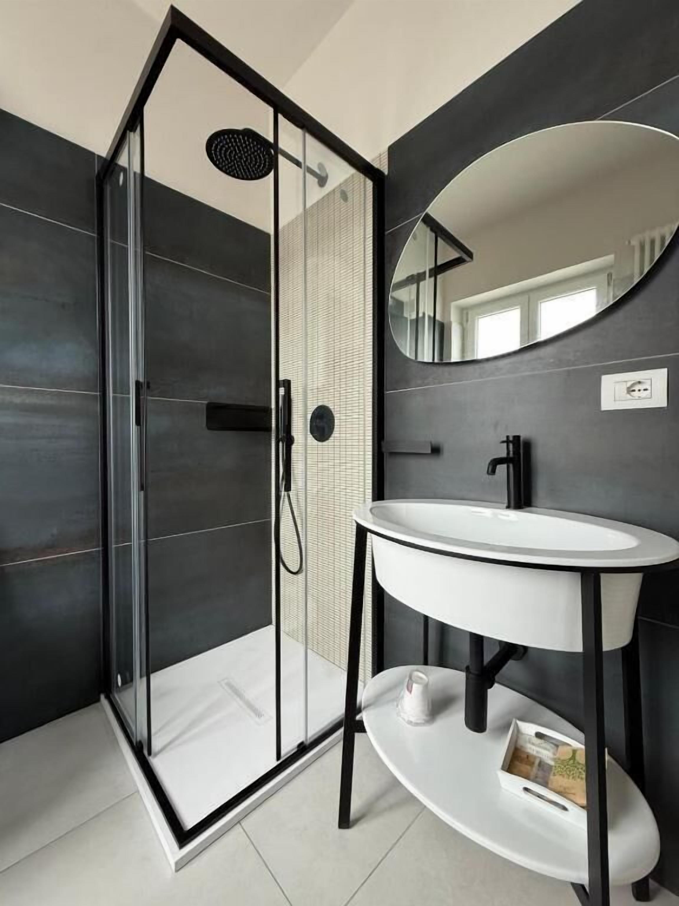 A modern bathroom with a glass-enclosed shower, a white sink, and a large mirror.