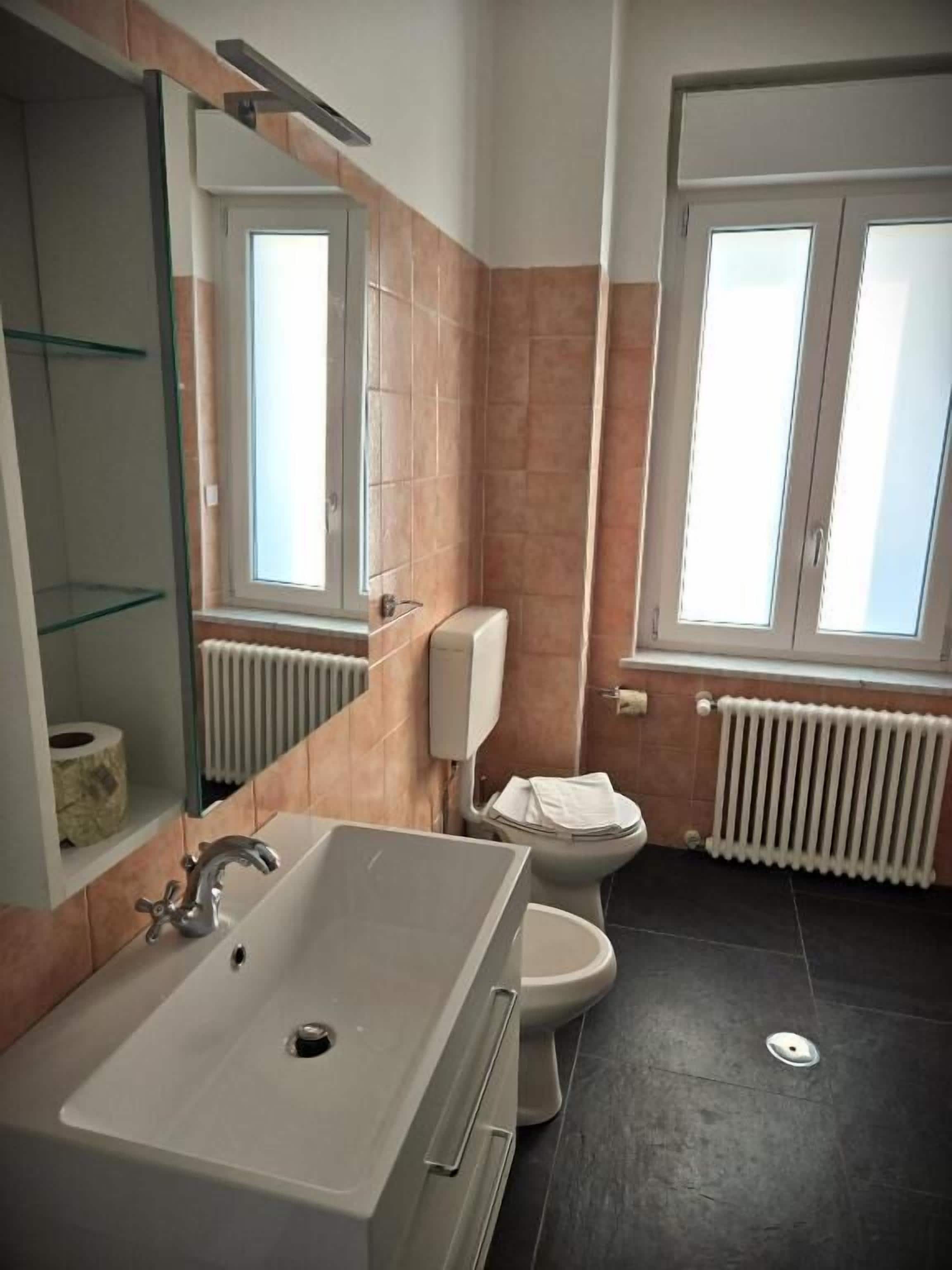 Ein Badezimmer mit Badewanne, Toilette und einem Fenster mit Tageslicht.