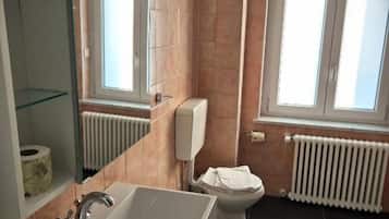 Ein Badezimmer mit Badewanne, Toilette und einem Fenster mit Tageslicht.