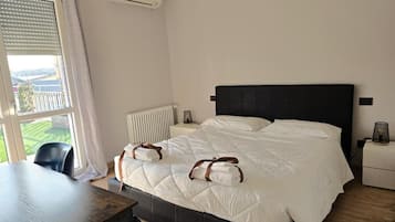 Ein Hotelzimmer mit Bett, Nachttischen, einem Fenster mit Jalousien und einer Klimaanlage.