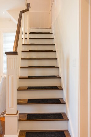 Una escalera con paredes blancas y escalones de madera.