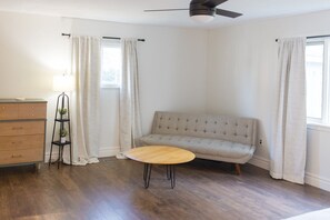 Une pièce comprenant un canapé, une petite table ronde, une commode et un lampadaire.