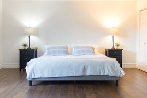 A bedroom with a bed, two bedside tables with lamps, and a door.