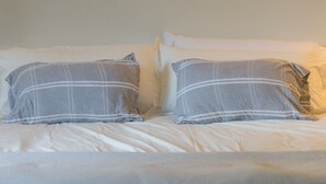 Un lit avec une literie blanche et deux oreillers à rayures grises et blanches.