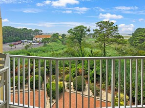A balcony with a view of a parking lot, greenery, and a distant building. - 2 Bedroom 2 Bathroom Condo With Outdoor Pool! Summer House 303 (Ocean City)