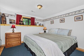 A bedroom with a bed, dresser, window with curtains, and wall decorations.