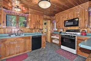 A wooden cabin-style kitchen with a built-in microwave, stove, and dishwasher.