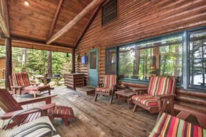 A log cabin with a porch, wooden furniture, and large windows. - Stepaway Vacation Rentals- Stoney End (St.Germain)