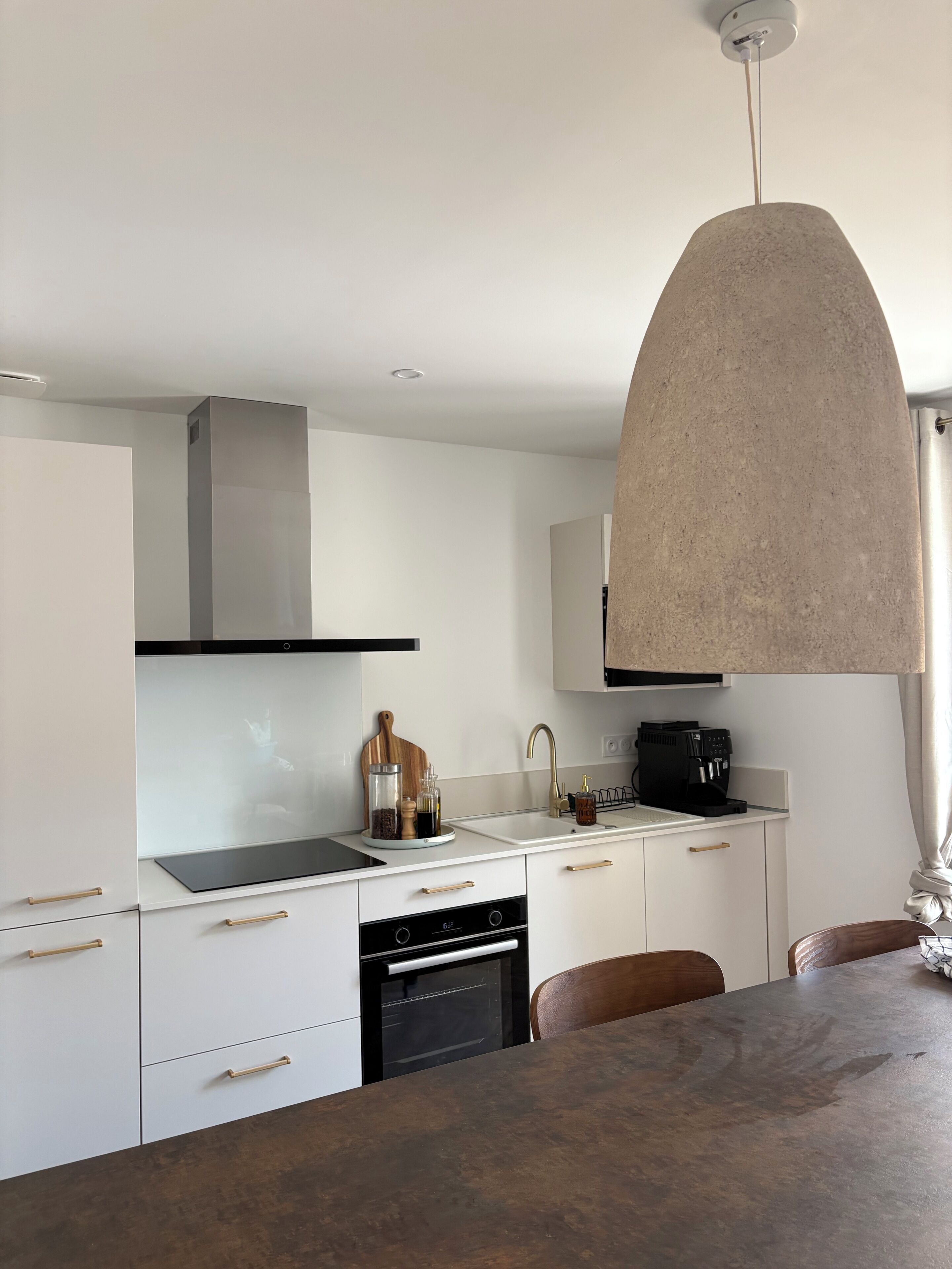 A modern kitchen with white cabinetry, a black stove, and a coffee machine.