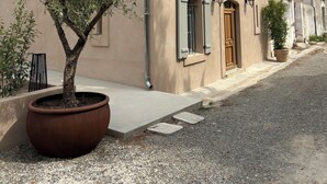 A two-story building with a beige facade, a potted tree in front, and a gravel driveway. - Pèira House • Swimming pool in the heart of the estate (shared with only one other house) (Bages)