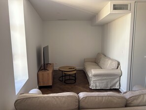 A modern living room with a sofa, a coffee table, and a television on a wooden stand. - Pèira House • Swimming pool in the heart of the estate (shared with only one other house) (Bages)