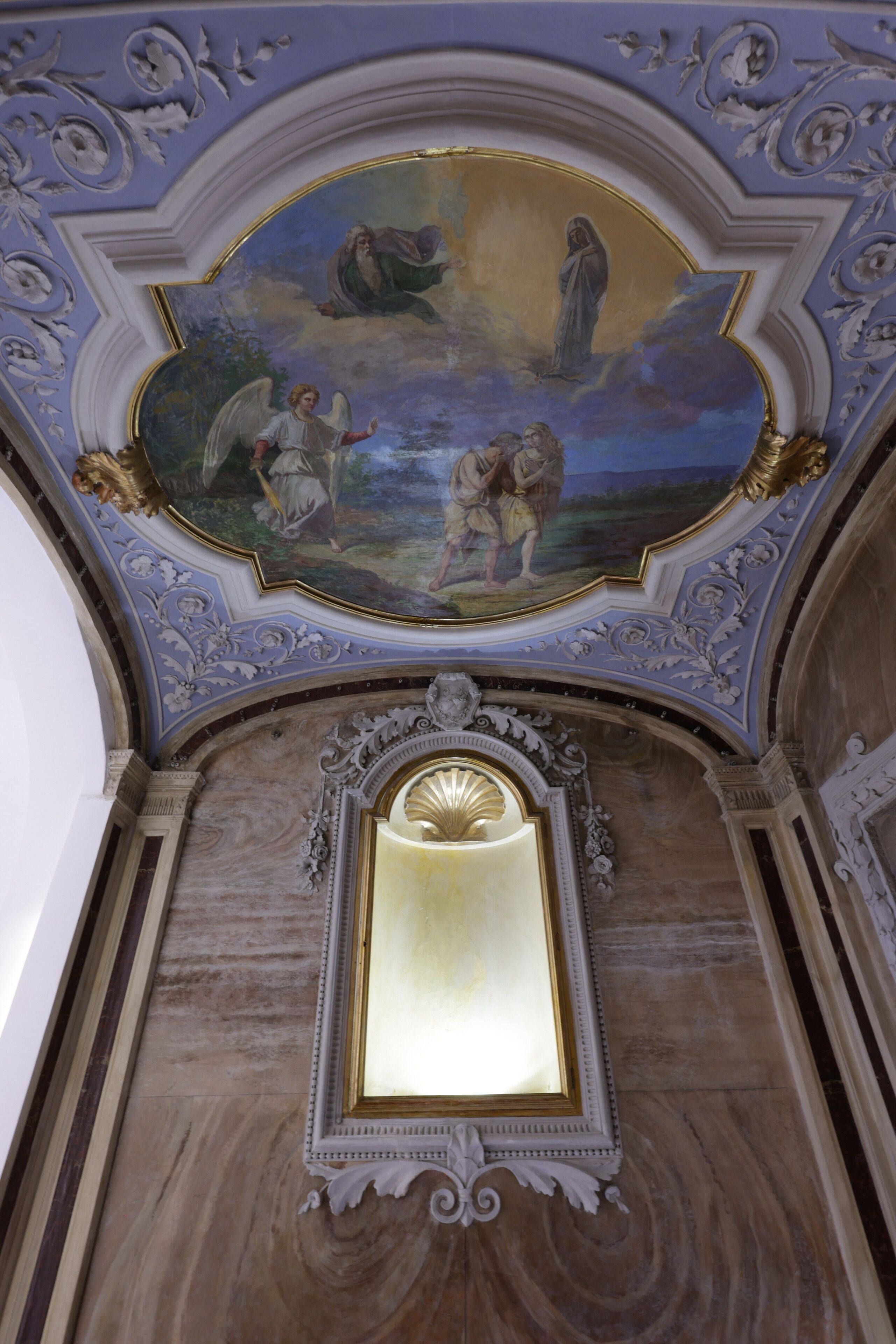 A ceiling with a fresco and a framed mirror.