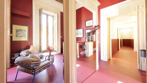 A room with a sofa, a table, and a chair. There is a door leading to another room. - Sancta Nolana (Naples)