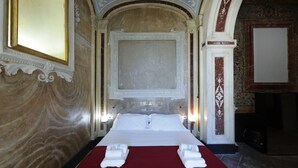 A hotel room with a large bed, a red bedspread, and a marble wall. - Sancta Nolana (Naples)