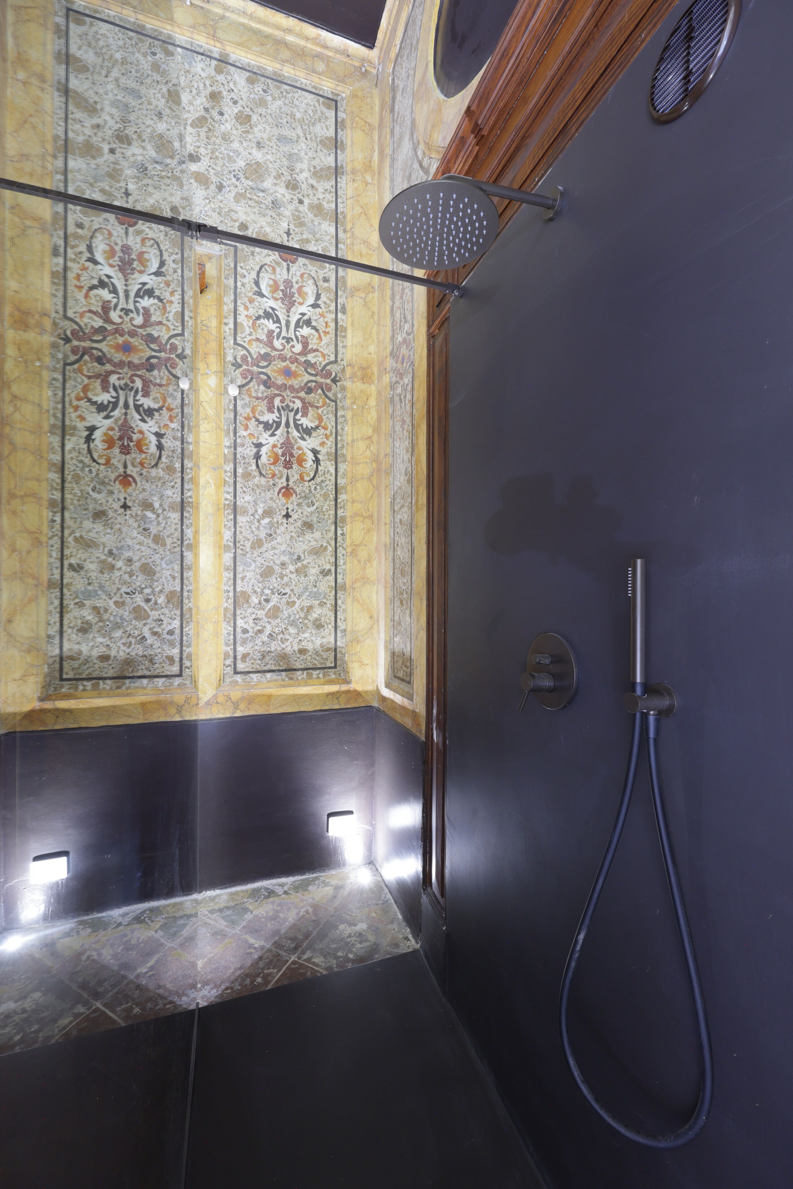 A bathroom with a shower, a decorative wall panel, and a marble floor.