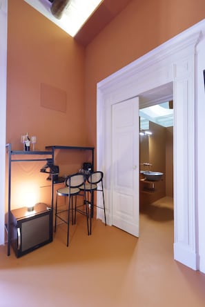 A compact room with a kitchenette, a dining area with chairs, and a white door leading to a bathroom. - Sancta Nolana (Naples)