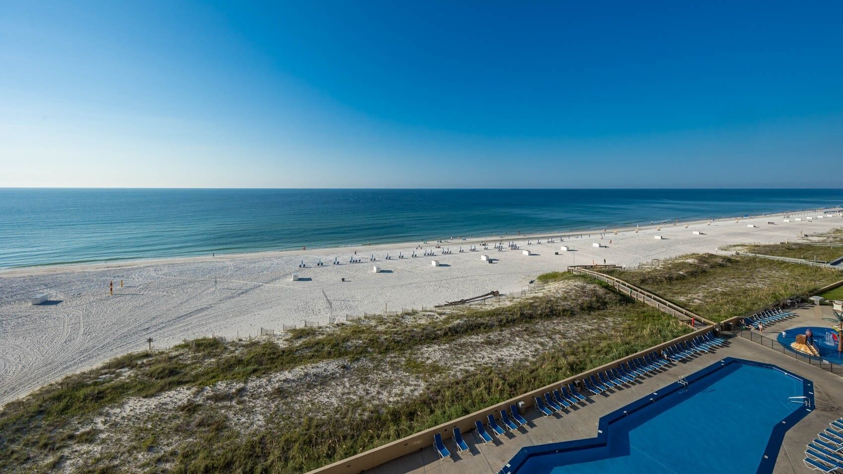 A beach resort with a swimming pool and beach chairs.