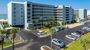 A multi-story hotel with a parking lot, palm trees, and a view of the beach. - Islander Beach Resort 506 2 Bedroom Condo (Fort Walton Beach)