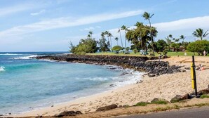 A beach with clear skies, a rocky shoreline, and palm trees. - Kauai Regency At Poipu Kai #823 3 Bedroom Condo (Koloa)