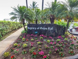 Schild für 'Regency at Poipu Kai' mit angelegten Gärten im Vordergrund.