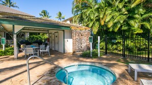 A pool area with a stone deck, a covered seating area, and a stone wall. - Kauai Regency At Poipu Kai #823 3 Bedroom Condo (Koloa)