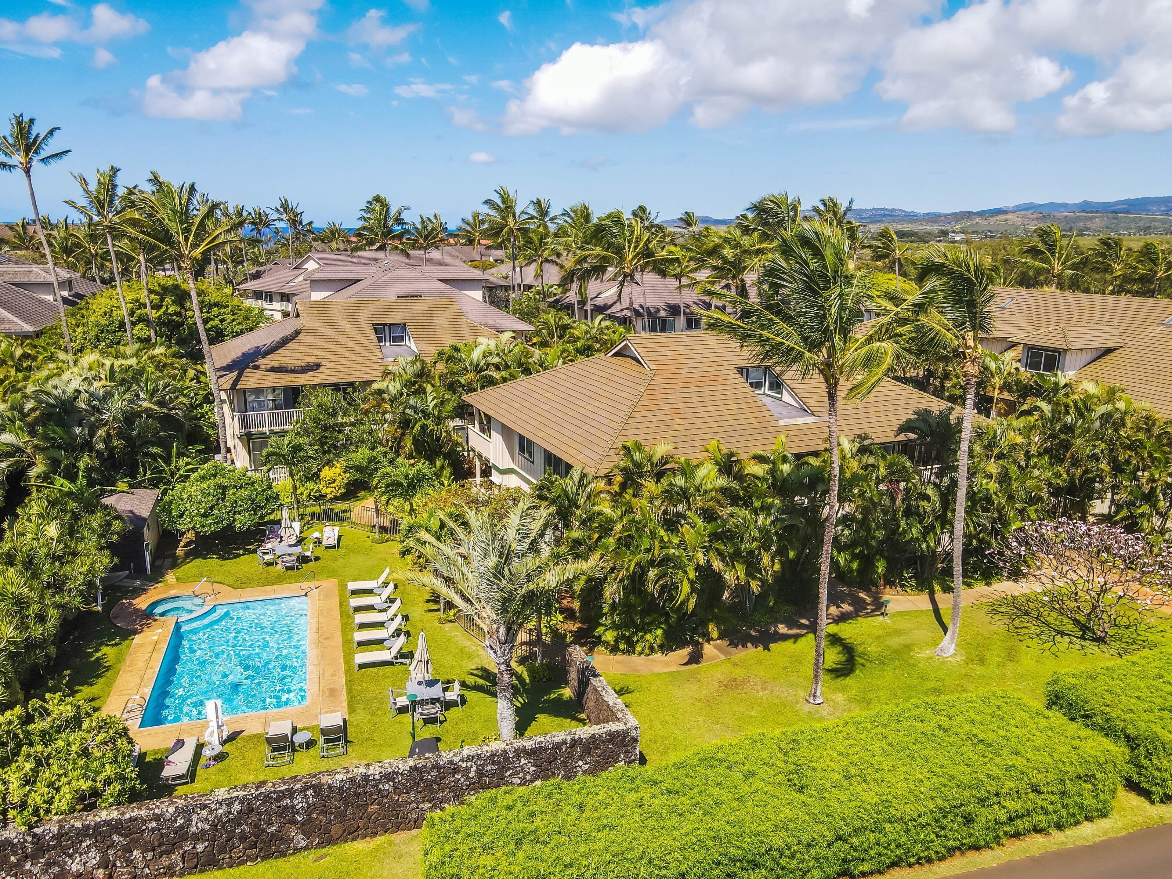 A resort with multiple buildings, a swimming pool, and lush greenery.