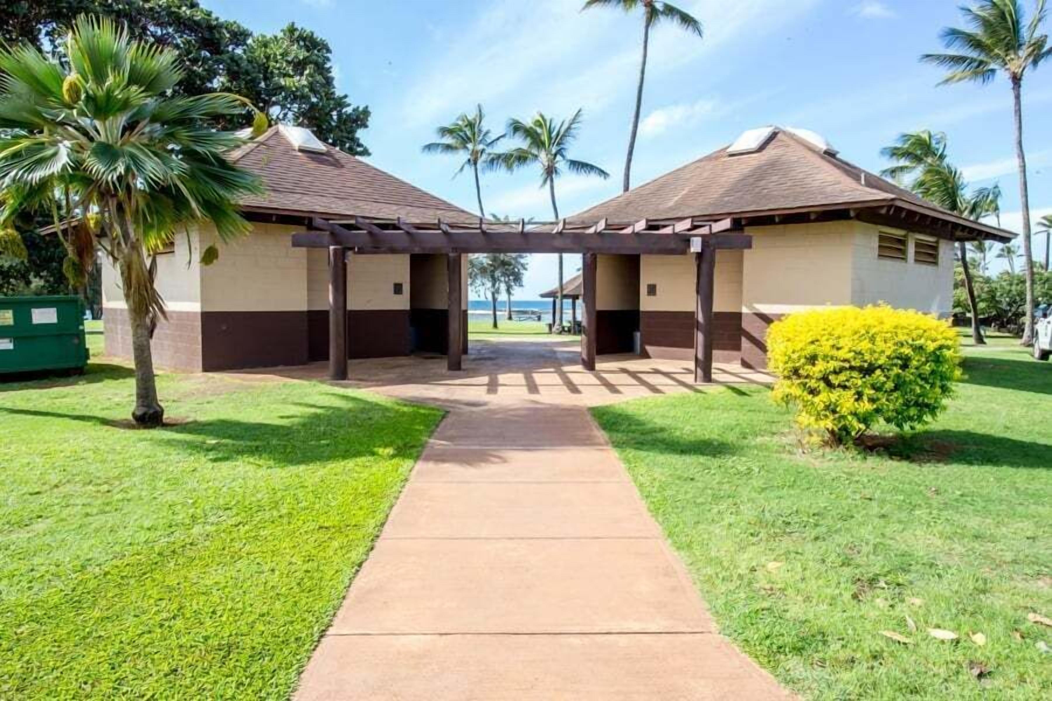 A covered walkway leading to two buildings with a view of the ocean.