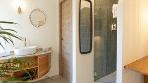 Une salle de bain moderne avec un lavabo blanc, un meuble-lavabo en bois et une cabine de douche en verre.