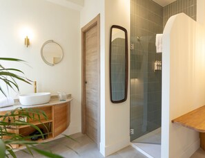 Ein modernes Badezimmer mit Waschbecken, Holz-Waschtisch und einer Duschkabine aus Glas.