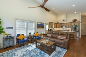 A spacious living room with a brown leather sofa, blue armchairs, and a wooden coffee table. - Murray Creek Hollow - Private Asheville Escape (Asheville)