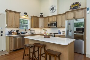 Une cuisine moderne avec des meubles en bois, des appareils en acier inoxydable et un grand îlot central doté de tabourets.