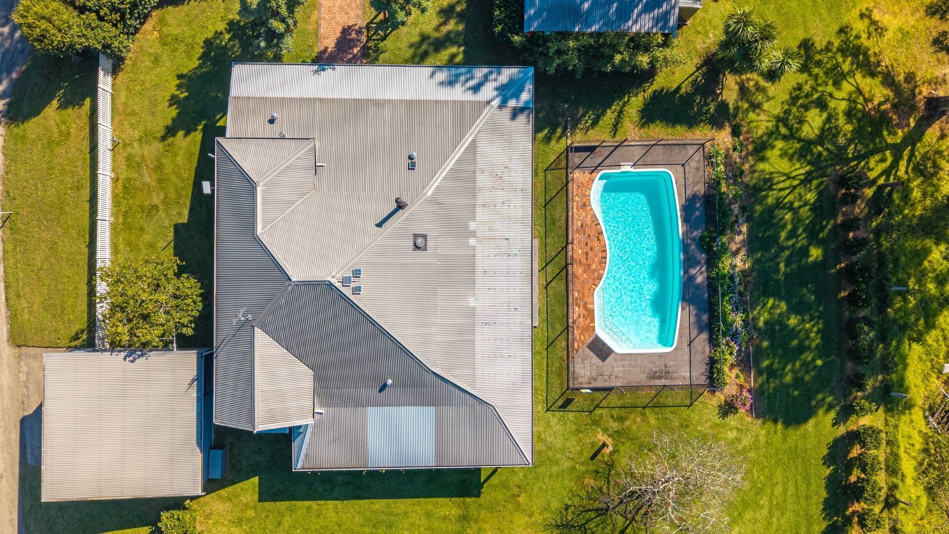 A residential property with a large house, a swimming pool, and surrounding greenery.