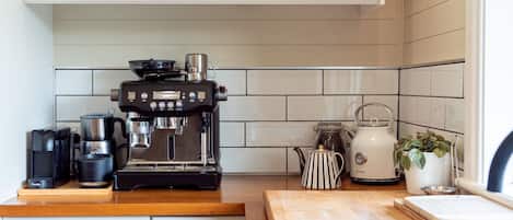 Et køkken med en Breville espressomaskine, en elkedel og en kaffemaskine på bordet.