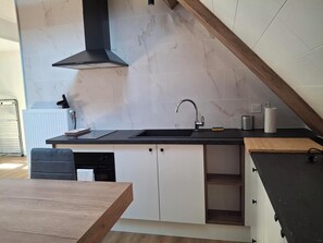 Eine moderne Küche mit schwarzem Arbeitsplatz, weißen Schränken und einer schwarzen Dunstabzugshaube.