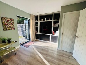 A room with a sliding glass door leading to a patio, a bookshelf, and a television. - #13 Elegant Solihull Townhouse Sleeps 10 NEC/BHX (Solihull)