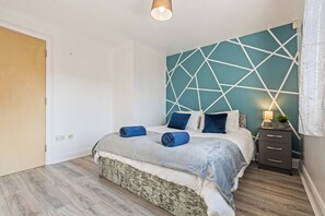 A bedroom with a bed, a nightstand, and a wall with geometric patterns. - #130 Free Parking Stylish Apt City Centre|sleeps 6 (West Midlands)