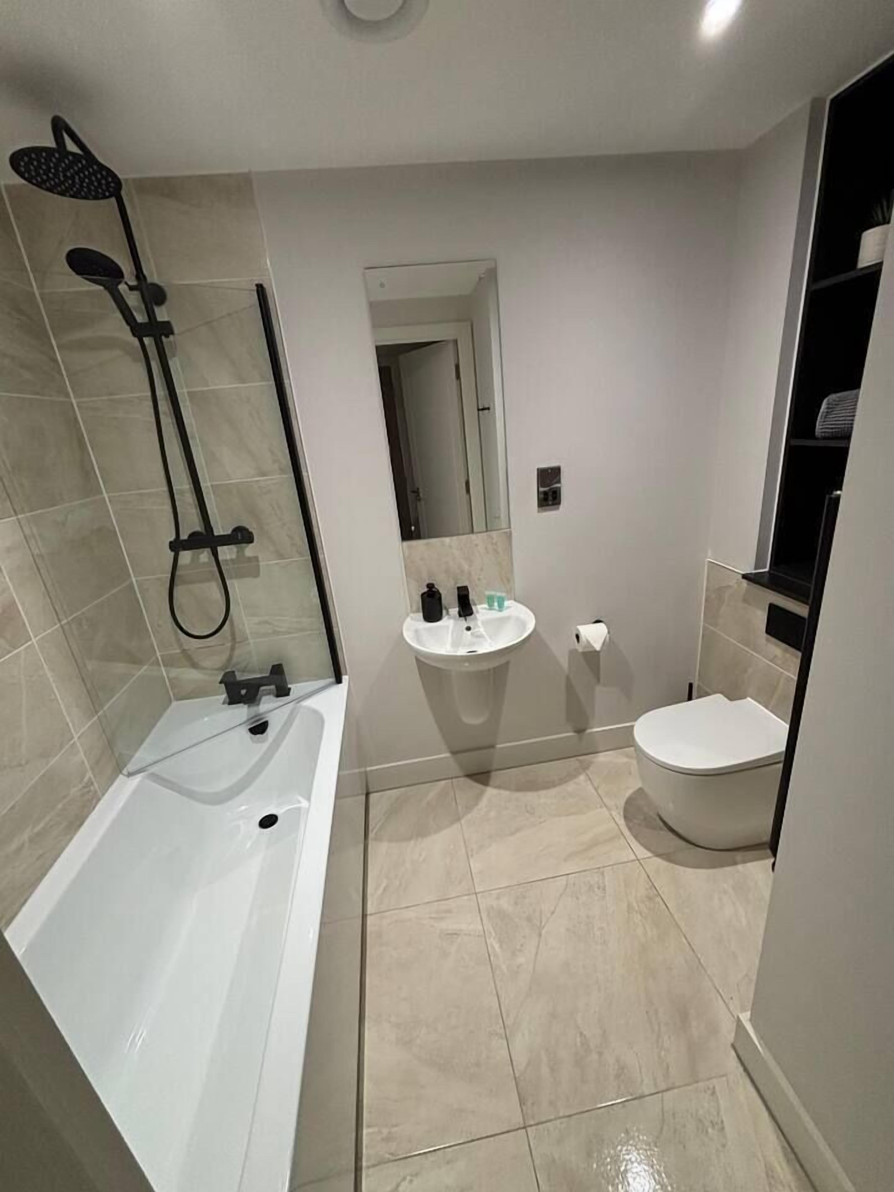 A modern bathroom with a bathtub, toilet, and shower.