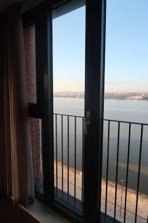 A room with a large window overlooking a body of water and a distant shoreline. - #132 Stylish Luxury Flat | Free Parking |City View (Merseyside)