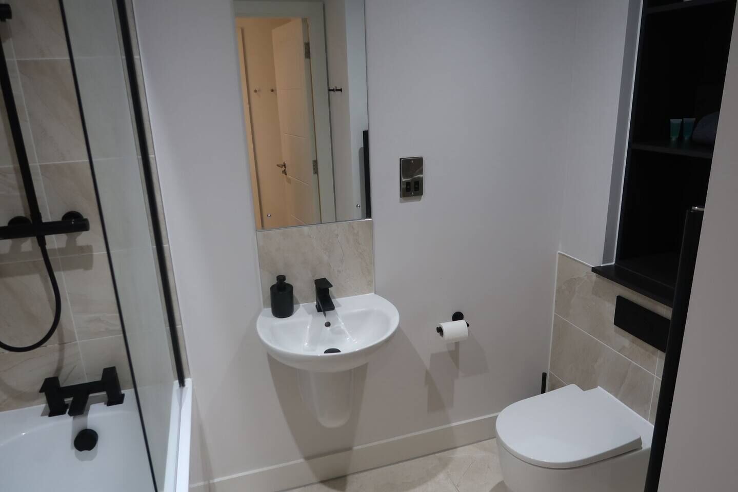 A bathroom with a white sink, toilet, and glass shower enclosure.