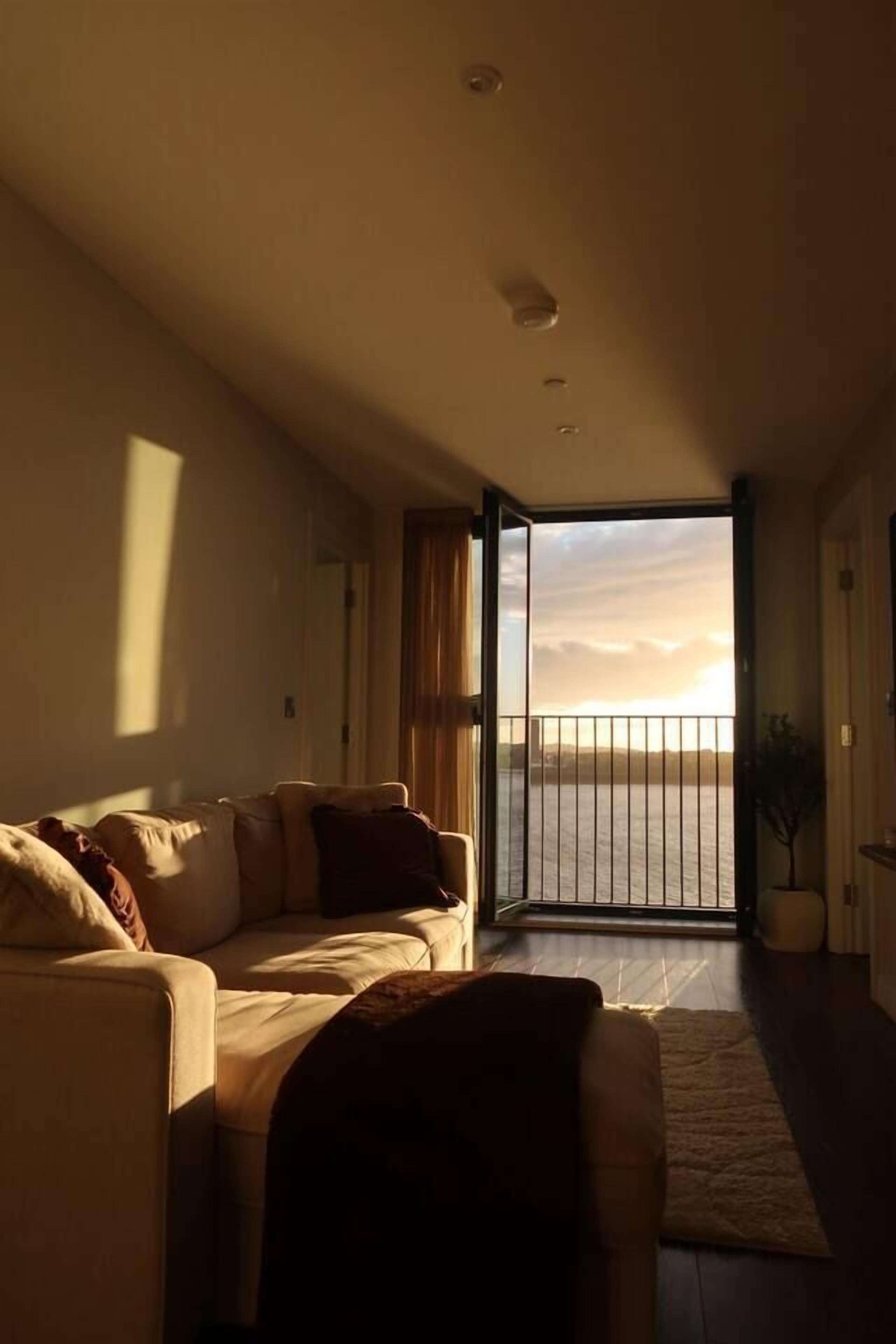 A living room with a sofa and a view of the sea through a balcony door.