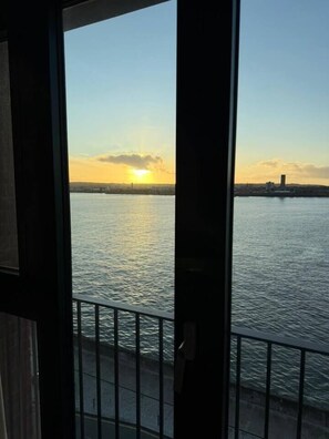A view of a body of water with a sunset, a distant city skyline, and a metal railing. - #132 Stylish Luxury Flat | Free Parking |City View (Merseyside)