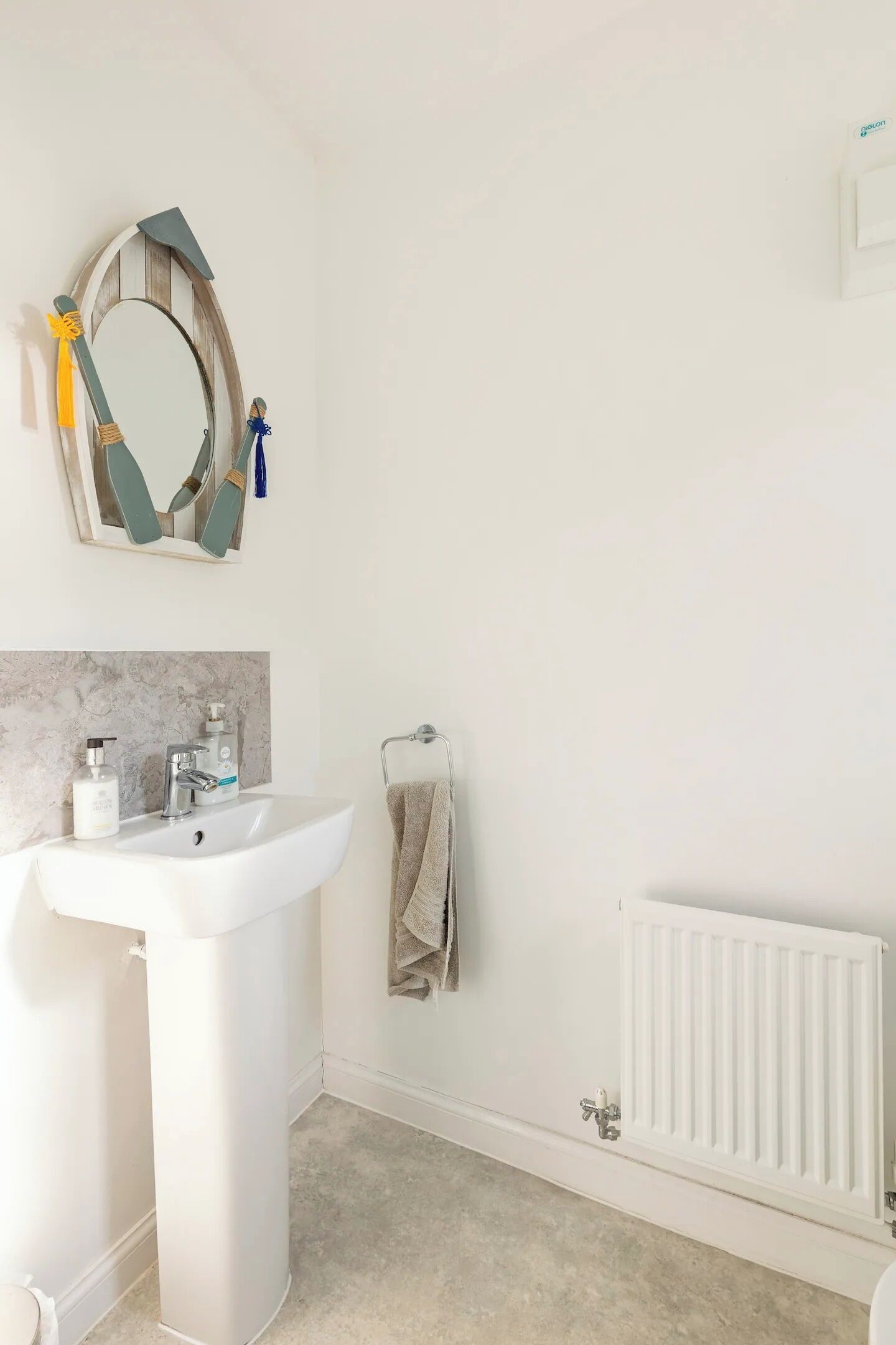 A bathroom with a white sink, a mirror with a wooden frame, a towel rack, and a radiator.