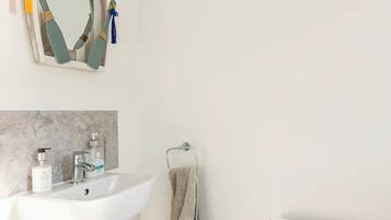 A bathroom with a white sink, a mirror with a wooden frame, a towel rack, and a radiator.