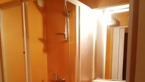 Un baño con ducha, lavamanos y espejo.