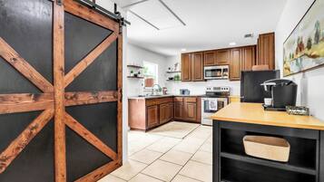 Une cuisine avec des meubles de rangement en bois, un réfrigérateur noir et une porte coulissante de style grange.