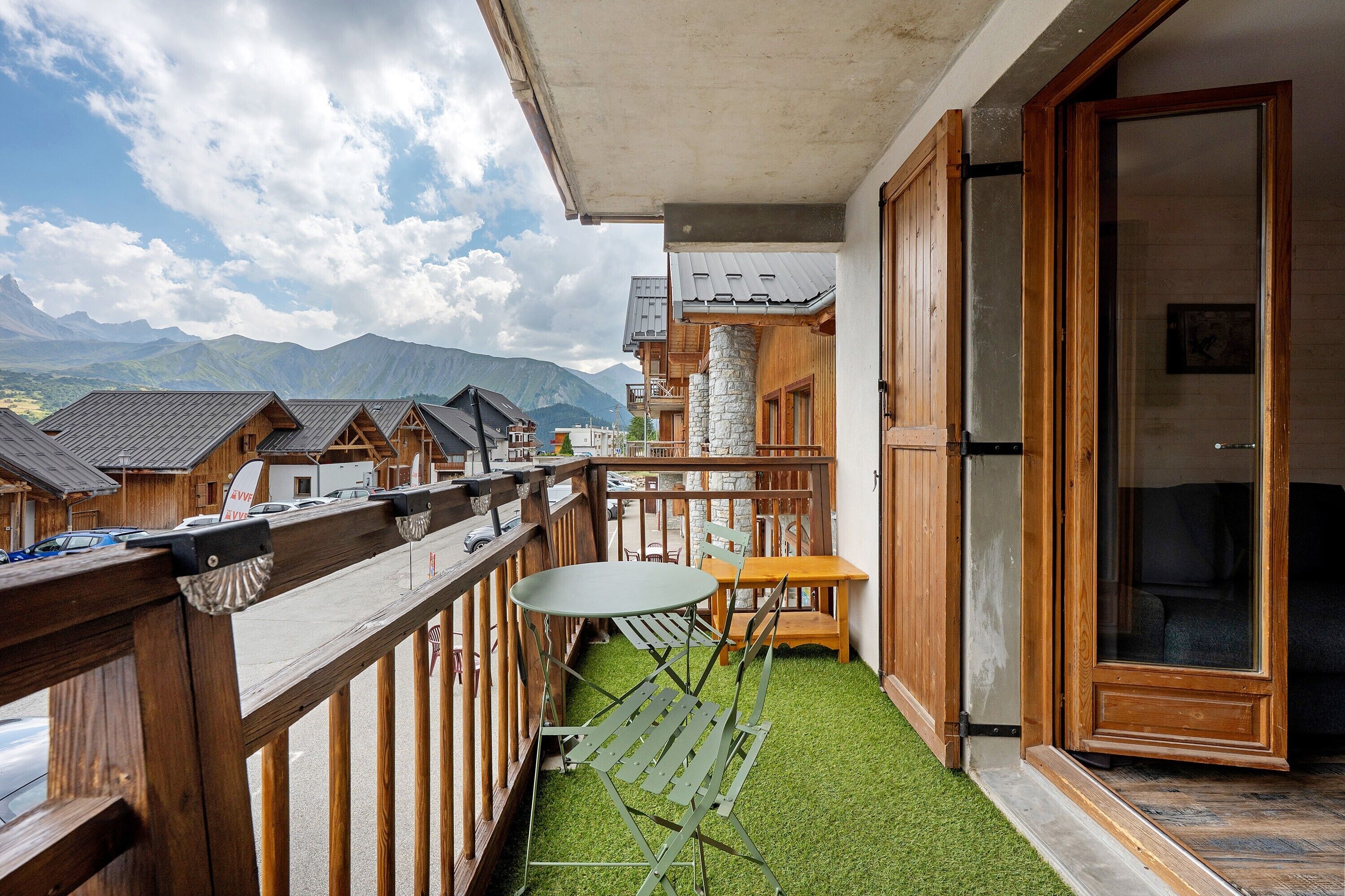 Een balkon met uitzicht op bergen, een houten hek en een tafel met stoelen.